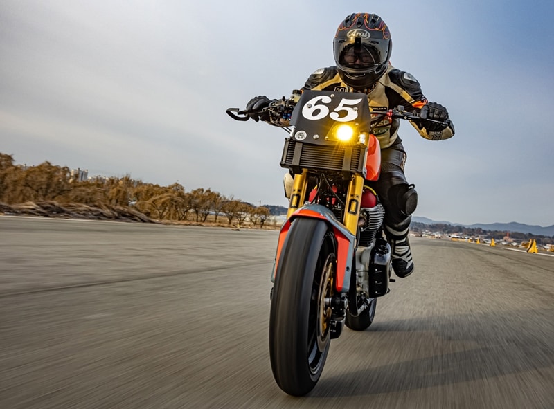 Kim installed the forks using modified Ducati triple trees, with custom bars, a STACK racing tacho, and a Yoshimura digital temperature meter completing the cockpit. A Lithium-ion battery supplies juice to the starter motor, the halogen headlight and LED tail lamp, plus what’s left of the wiring loom. (Source: Bikeexif)