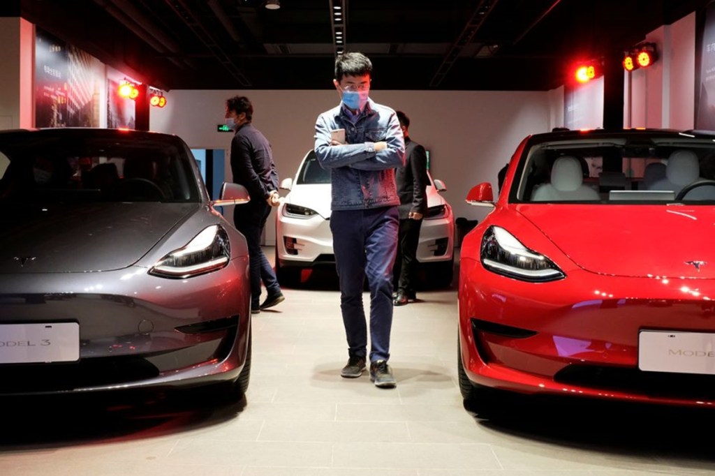 A man wearing a face mask following the coronavirus disease (COVID-19) outbreak walks by Tesla Model 3 sedans and Tesla Model X sport utility vehicle at a new Tesla showroom in Shanghai, China (Reuters)