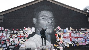 Street artist Akse P19 repairs defaced mural of UK soccer star Marcus Rashford after England lost the Euro 2020 soccer championship final match to Italy. (Photo by AP)