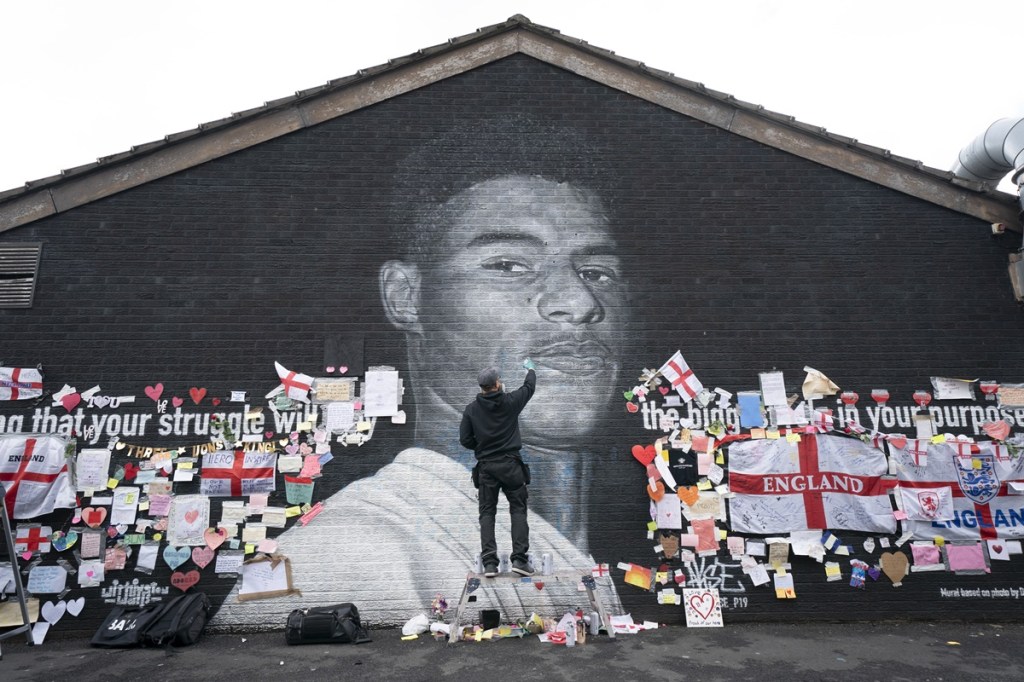 Street artist Akse P19 repairs defaced mural of UK soccer star Marcus Rashford after England lost the Euro 2020 soccer championship final match to Italy. (Photo by AP) Street artist Akse P19 repairs defaced mural of UK soccer star Marcus Rashford after England lost the Euro 2020 soccer championship final match to Italy. (Photo by AP)