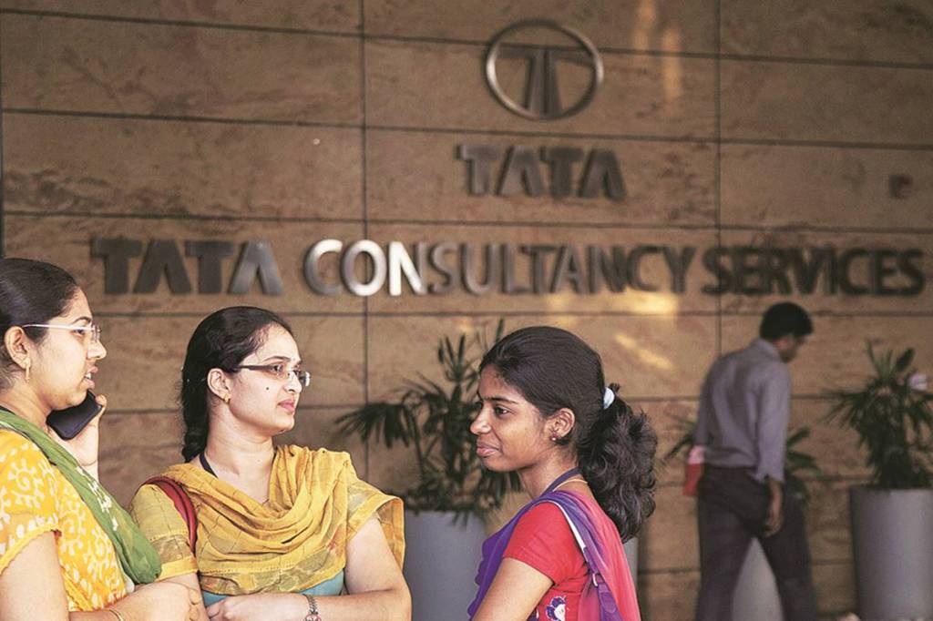Employees stand near a signage for Tata Consultancy Services Ltd. (TCS) at the company's Synergy Park campus in Hyderabad, India, on Monday, April 11, 2016. TCS, India's largest software exporter, is scheduled to announce earnings on April 18. Photographer: Namas Bhojani/Bloomberg