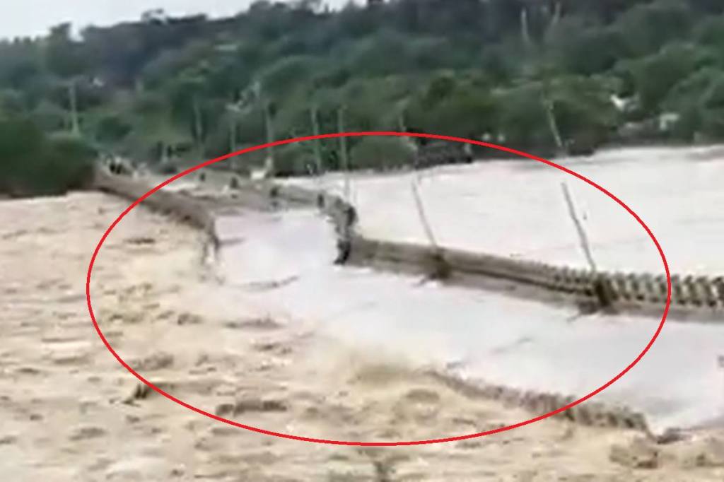 The video shows the river water flowing over the bridge and the bridge collapsing within seconds due to the sheer force of the water.