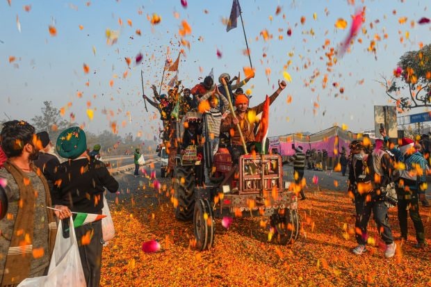 Farmers shower flower petals on fellow farmers riding on their tractors after breaking the police barricades at Singhu border during the 'Kisan Gantantra Parade' on Republic Day, in New Delhi on January 26, 2021. (PTI Photo)