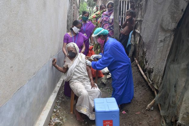 A health worker inoculates an old woman with Covishield vaccine during a door-to-door vaccination drive, at Chitnan village at Vatora Island in Howrah on June 29, 2021. (PTI Photo)