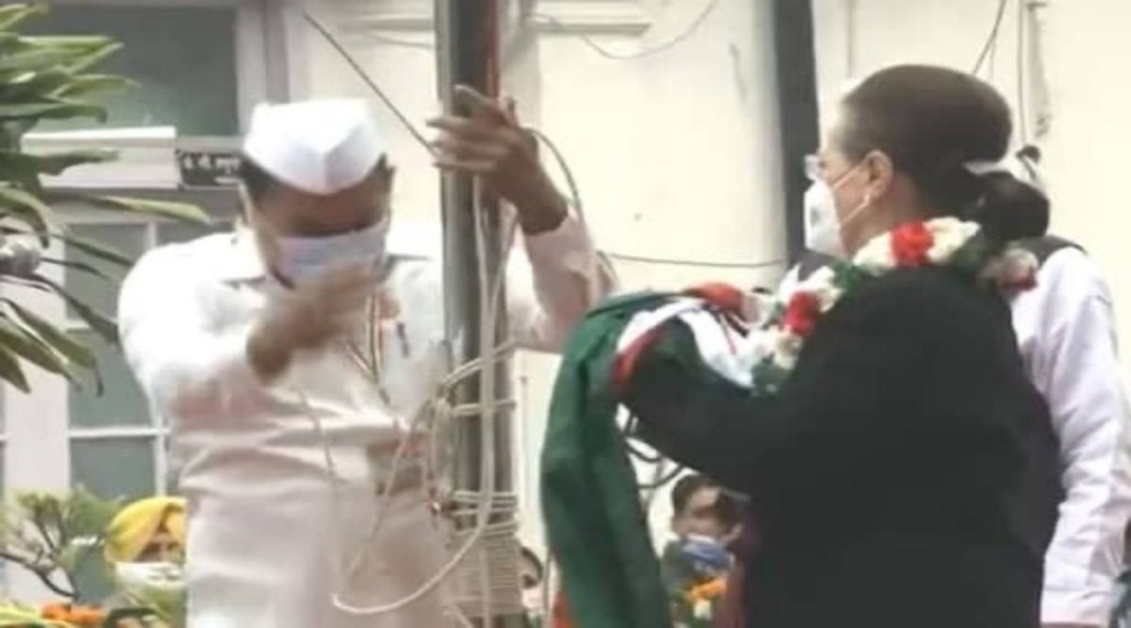 Sonia Gandhi can be seen trying to pull the flag to unfurl it while she is being assisted by a party member. Sonia Gandhi can be seen trying to pull the flag to unfurl it while she is being assisted by a party member.