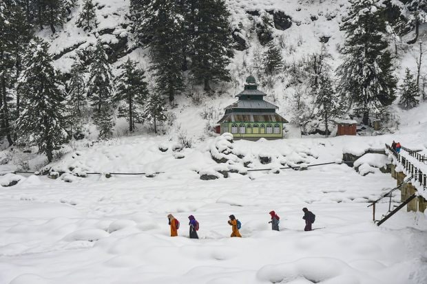 Students walk through snow as they return from a government tuition centre, after recent snowfall at a village at Tangmarg in Baramulla district. (PTI Photo)