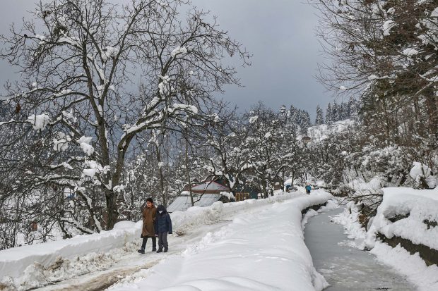 Children walk on a snow-covered road after recent snowfall at a village at Tangmarg, in Baramulla district. (PTI Photo)