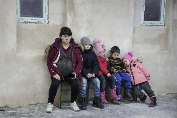 Mariupol: A pregnant woman and children sit on a bench in the improvised bomb shelter in a sports center, which can accommodate up to 2000 people, in Mariupol, Ukraine. (AP Photo)