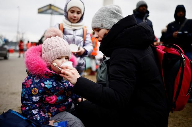 A mother gives water to her daughter as they flee Russian invasion of Ukraine, at a temporary camp in Przemysl, Poland. (Reuters Photo)