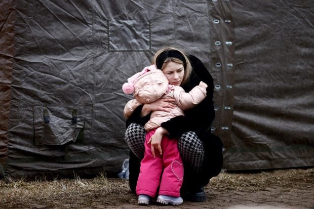 A woman fleeing Russian invasion of Ukraine hugs a child at a temporary camp in Przemysl, Poland. (Reuters Photo)
