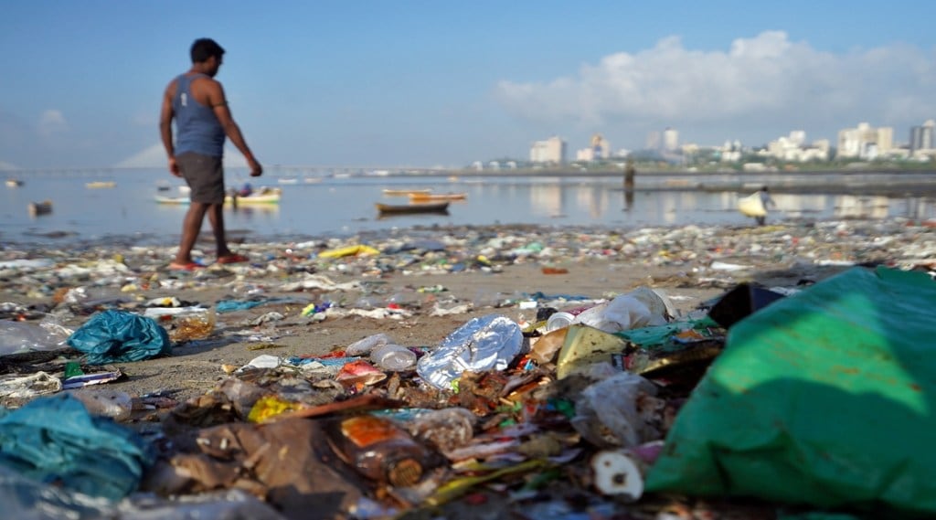 FILE PHOTO: A man walks on a garbage-strewn beach in Mumbai