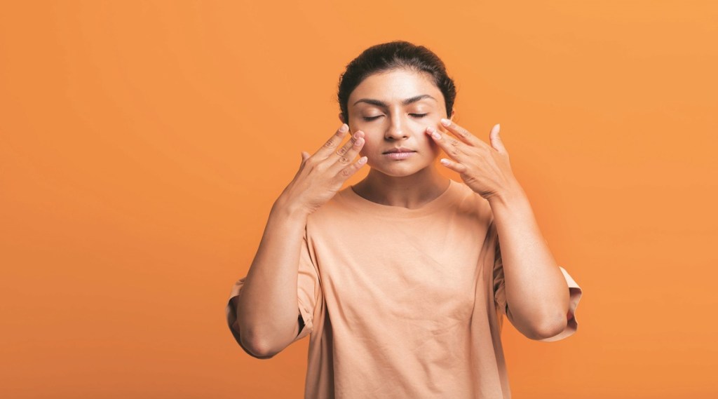 Close up portrait of young indian american woman doing facebuilding yoga face gymnastics yoga self massage.