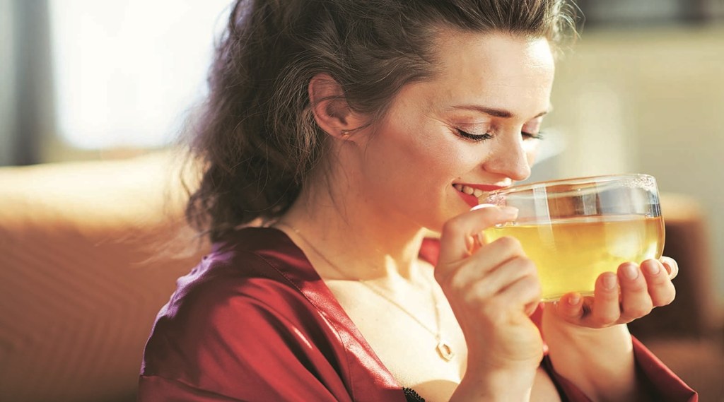 happy woman in modern house in sunny day drinking cup of tea