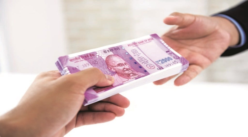 Businessman handing over wad of crisp new Indian rupee banknote money to his partner against white blur background Businessman handing over wad of crisp new Indian rupee banknote money to his partner against white blur background