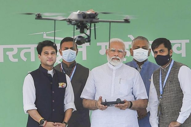 Prime Minister Narendra Modi flies a drone at the inauguration of the Bharat Drone Mahotsav, at Pragati Maidan in New Delhi. Union Minister for Civil Aviation Jyotiraditya M. Scindia and Union MoS for Civil Aviation General VK Singh are also seen. (PTI Photo)