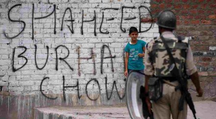 A boy stands next to a wall painted with graffiti as an Indian policeman stands guard during a protest in Srinagar against the recent killings in Kashmir, July 22, 2016. | Danish Ismail/Reuters A boy stands next to a wall painted with graffiti as an Indian policeman stands guard during a protest in Srinagar against the recent killings in Kashmir, July 22, 2016. | Danish Ismail/Reuters