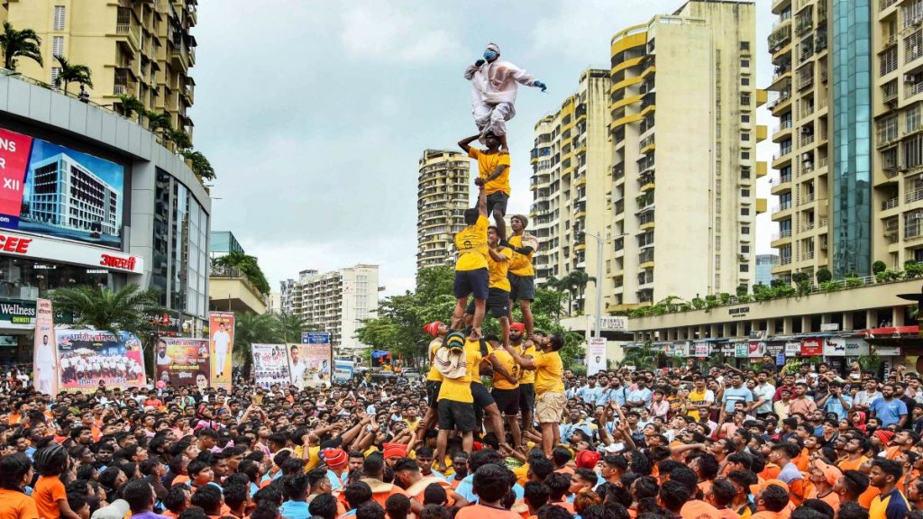 A 'govinda', atop a human pyramid, wears a PPE kit to attend a 'Dahi Handi' festival on the occasion of Krishna Janmashtami, in Navi Mumbai, Friday. (Photo: PTI) A 'govinda', atop a human pyramid, wears a PPE kit to attend a 'Dahi Handi' festival on the occasion of Krishna Janmashtami, in Navi Mumbai, Friday. (Photo: PTI)