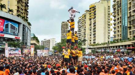 A 'govinda', atop a human pyramid, wears a PPE kit to attend a 'Dahi Handi' festival on the occasion of Krishna Janmashtami, in Navi Mumbai, Friday. (Photo: PTI)