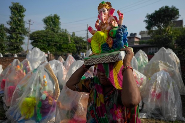 An artist carries an idol of Hindu god Ganesha to display for sale ahead of Ganesh Chaturthi festival, in Jammu, India, Monday, Aug. 22, 2022. The idols are in demand ahead of the festival that celebrates the birthday of the elephant headed god. (AP Photo)