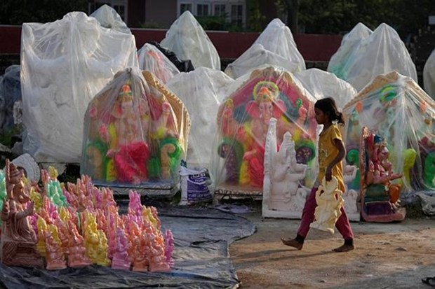 A girl carries an idol of Hindu god Ganesha being prepared for sale ahead of Ganesh Chaturthi festival, in Jammu, India, Monday, Aug. 22, 2022. The idols are in demand ahead of the festival that celebrates the birthday of the elephant headed god. (AP Photo)