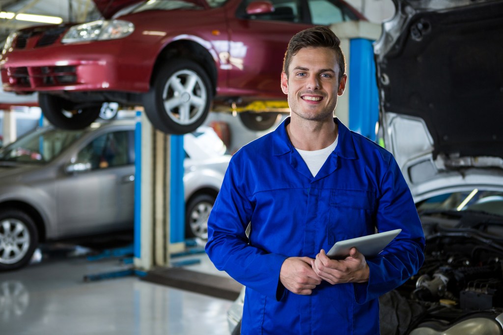 Portrait of mechanic holding digital tablet at repair garage.