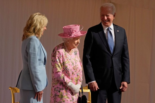 US President Joe Biden and first lady Jill Biden smile while standing with Britain's Queen Elizabeth II watching a Guard of Honour march past before their meeting at Windsor Castle near London, June 13, 2021. (AP Photo)