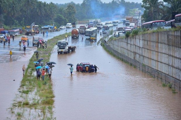 Ramnagar: People push a car stuck on the flooded Bengaluru-Mysuru highway following heavy monsoon downpour at Ramnagar, Karnataka, Monday, Aug. 29, 2022. (PTI Photo)