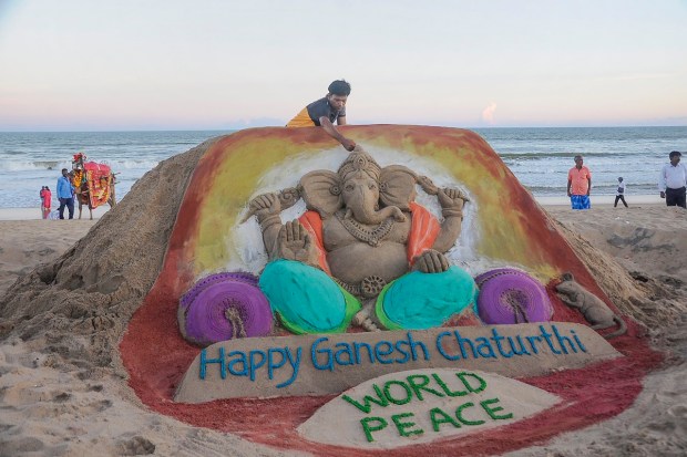Sculptor Manas Kumar Sahoo creates a sand sculpture of Lord Ganesh at Puri beach on the eve of Ganesh Utsav. (PTI Photo)