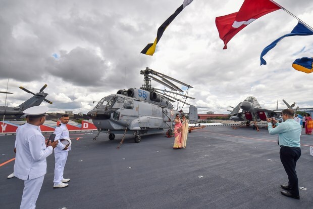 Kochi: Family members of Indian Navy personnel pose for photos with a Kamov-31 helicopter parked at the flight deck of the newly-commissioned indigenous aircraft carrier, INS Vikrant, at Cochin Shipyard Limited in Kochi, Friday, Sept. 2, 2022.(PTI Photo)