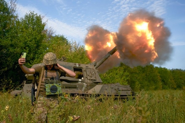 A Ukrainian soldier takes a selfie as an artillery system fires in the front line in Donetsk region, eastern Ukraine, Saturday, Sept. 3, 2022. (AP Photo)