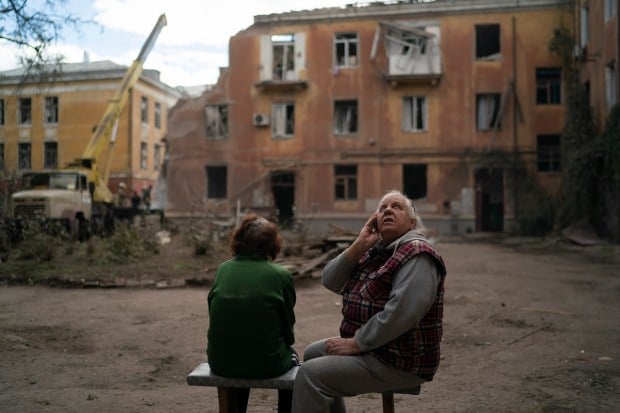 Raisa Smielkova, 75, looks up as she sits in front of the site where firefighters work to extinguish a fire as they look for potential victims after a Russian attack that heavily damaged a residential building in Sloviansk, Ukraine, Wednesday, Sept. 7, 2022. Smielkova was sleeping at the time of the explosion. 