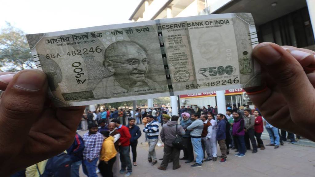 A man showing a currency note withdrawn from ATM while others waiting their turn in a long queue at an ATM in Sector 17 of Chandigarh on December 10, 2016. (Express Photo by Kamleshwar Singh)