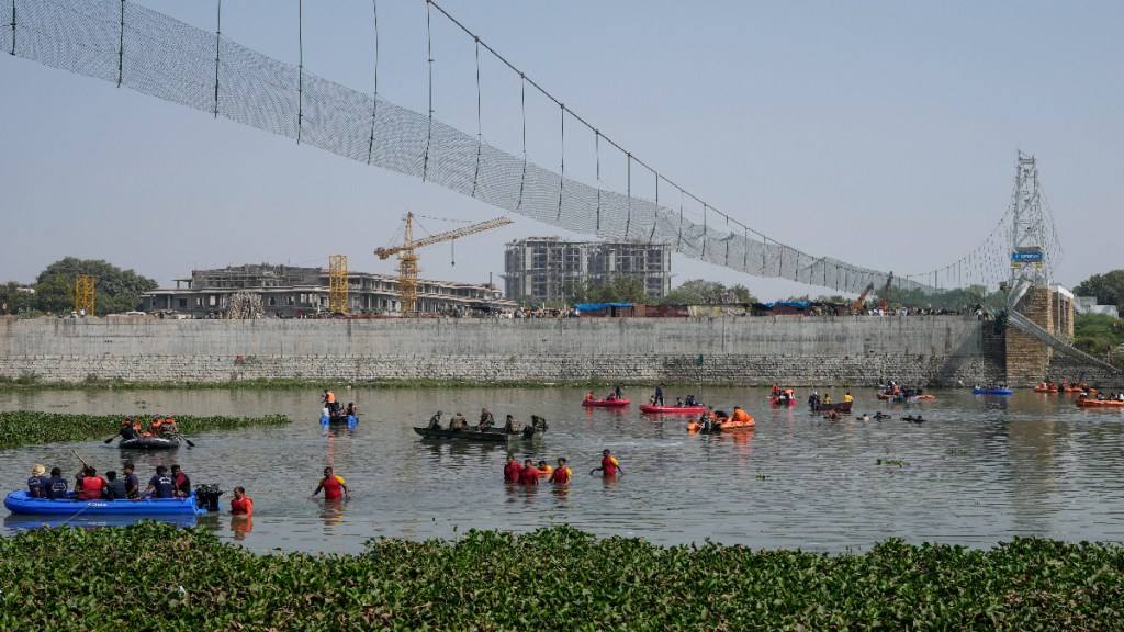 Rescuers on boats search in the Machchu river next to a pedestrian cable bridge that collapsed in Morbi town of western state Gujarat, India, Monday, Oct. 31, 2022. The century-old cable suspension bridge collapsed into the river Sunday evening, sending hundreds plunging in the water, officials said. (AP Photo/Ajit Solanki)