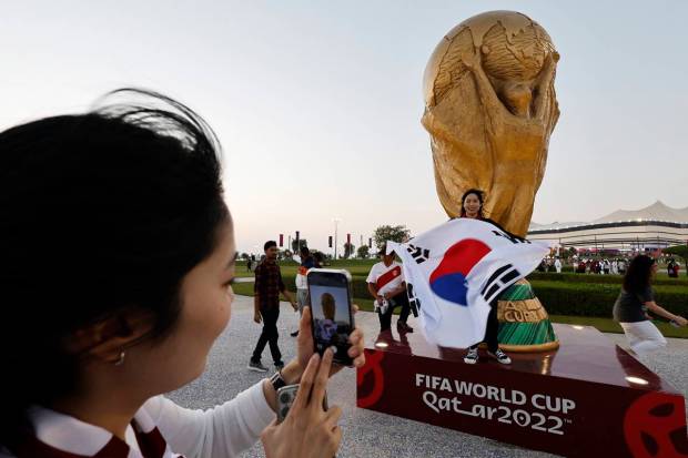 A South Korea fan poses for a photo infront of a replica of the world cup outside the stadium before the match. (Reuters Photo)