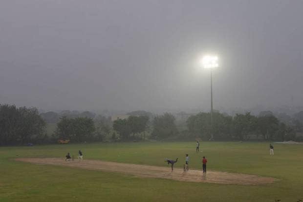People play cricket surrounded by evening haze and toxic smog on the outskirts of New Delhi. (AP Photo)