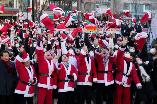 South Korean Prime Minister Han Duck-soo, fourth from right, and volunteers clad in Santa Claus costumes throw their hats in the air during a Christmas charity event before they deliver gifts for the underprivileged in Seoul, South Korea on Saturday. (Image: AP)