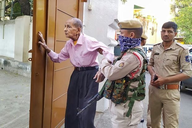 A policeman helps an elderly voter arrived to cast his vote during the first phase of Gujarat Assembly elections in Rajkot. (Image/PTI)