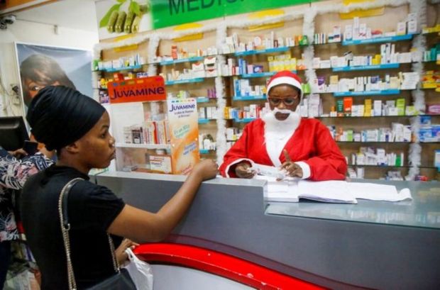 An employee dressed as Santa Claus receives a customer ahead of the Christmas celebrations at a drug store in Abidjan, Ivory Coast. (Image: Reuters)