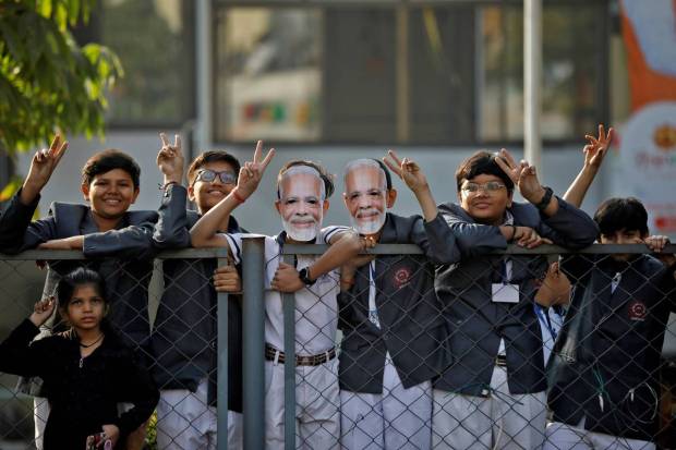 School children gesture towards Prime Minister Narendra Modi as he arrives to cast his vote during the second and last phase of Gujarat state assembly elections in Ahmedabad. (Reuters Photo)