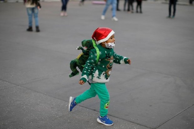 A boy wearing a Santa Claus hat runs at Zocalo Square ahead of Christmas in Mexico City. (Image: Reuters)