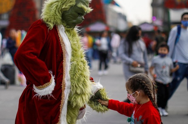 A person dressed as the grinch holds a hand of a girl at Zocalo Square ahead of Christmas in Mexico City. (Image: Reuters)