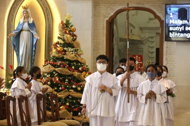 A server carries a cross during a Christmas Eve service at a cathedral in Denpasar, Bali. (Image: AP)