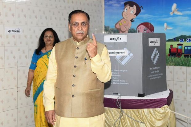 Former Gujarat chief minister Vijay Rupani shows his finger marked with indelible ink after casting his vote during the first phase of Gujarat Assembly elections in Rajkot. (Image/PTI)