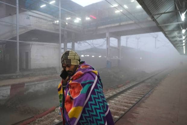 A person talks on his mobile phone as he waits for his train amidst heavy morning fog in Varanasi, in the northern Indian state of Uttar Pradesh. (AP Photo)