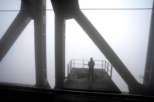 A person watches as a train moves past a bridge over the river Ganges amidst heavy morning fog in Varanasi, in the northern Indian state of Uttar Pradesh. (AP Photo)