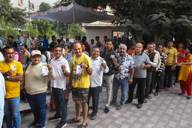 Vadodara: Voters show their identification cards as they wait in a queue to cast their votes at a polling booth during the second and final phase of Gujarat Assembly elections, in Vadodara. (PTI Photo)