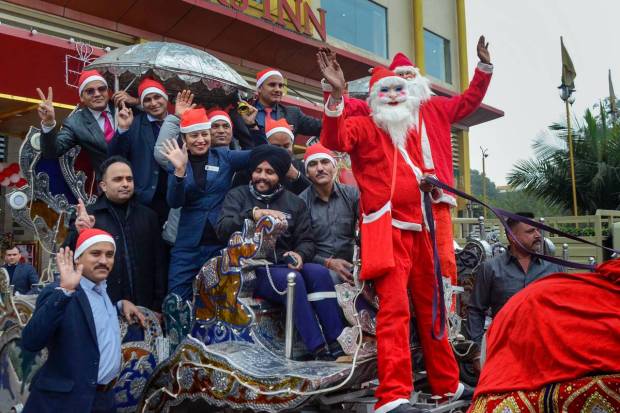Amritsar: Men dressed as Santa Claus along with hotel staff ride on a horsecart during Christmas celebrations, in Amritsar. (PTI Photo)