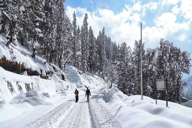 People walk on the snow covered road following snowfall at South Portal of the Atal Tunnel in Rohtang, on Jan 14, 2023. (Image: PTI)