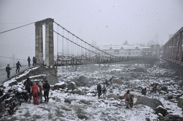 Tourists walk amid fresh snowfall during the fresh snowfall at Nehru Kund in Manali. (Image: PTI)