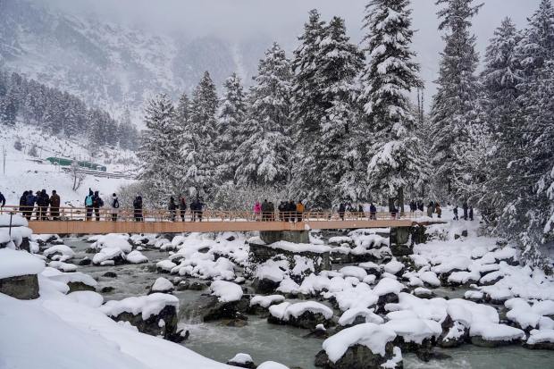  Tourists cross a bridge after fresh snowfall at Sonamarg in Ganderbal district of Kashmir (PTI Photo)